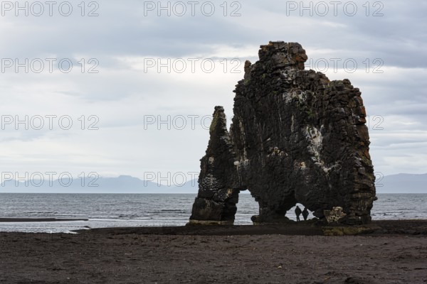 Tourists, couple at the basalt rock Hvitserkur, famous Elephant Rock at the lava beach, coastline, Vatnsnes peninsula, Hunafjördur, North Iceland, Iceland
