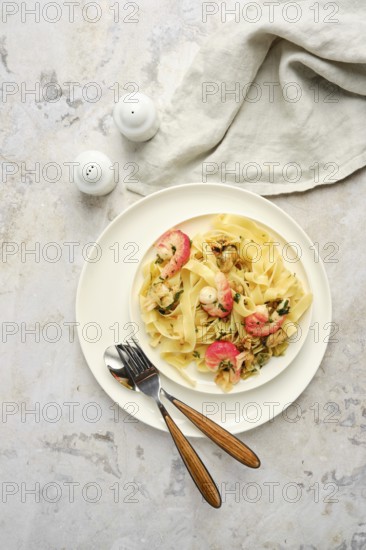 Delicious fettuccine allo Scoglio features an array of seafood mixed with pasta, presented elegantly on a white plate. A cozy dining atmosphere is enhanced by simple cutlery and salt shakers