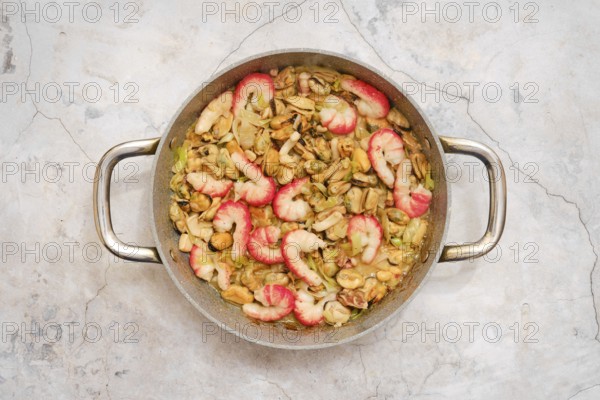 Overhead view of pan with tender shrimp, octopus and mussels with leek