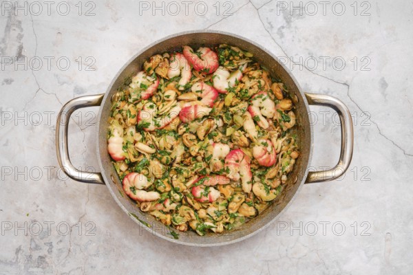 Seasoned ingredients allo scoglio features an assortment of seafood, including shrimp and clams, tossed with fresh herbs, and served in a rustic stainless steel pan