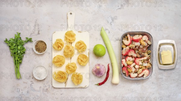 Fresh ingredients for fettuccine allo scoglio, including seafood, pasta, herbs, and vegetables. This colorful assembly showcases the vivid elements ready for cooking
