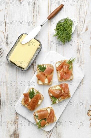 Delicious smoked herring caviar layered on cream cheese spread over crusty bread slices, topped with fresh dill. The setup features a butter dish and a knife, creating a charming culinary display