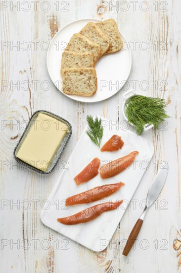 Herring caviar lay on a white cutting board beside a butter dish and sliced bread. Green dill adds a vibrant touch, suggesting a flavorful meal about to be prepared for dining