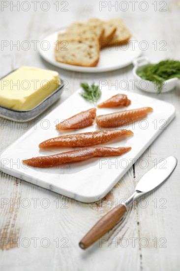 A platter features salted herring caviar arranged neatly alongside slices of bread and a portion of butter. The rustic wooden table adds a warm ambiance to the culinary display