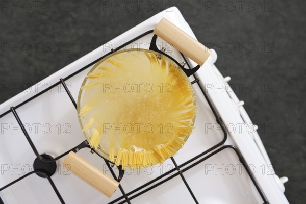 Overhead view of cooking spaghetti pasta in a pot with boiling water on a gas stove