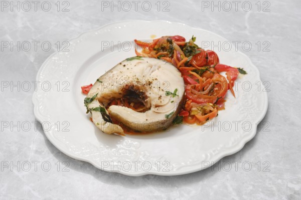 A succulent fish fillet, garnished with herbs, is presented alongside a colorful salad of sliced vegetables