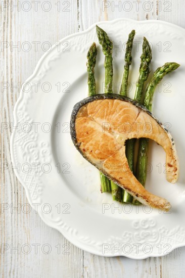 Grilled salmon on a round white dish alongside roasted asparagus spears. The vibrant green asparagus contrasts beautifully with the orange salmon, creating an appealing presentation