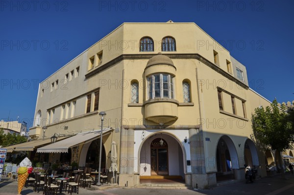 Town hall, backside, yellow historical building with arched windows, outside tables and chairs, sunny sky in mediterranean town, Kos town, Kos, Dodecanese, Greek Islands, Greece