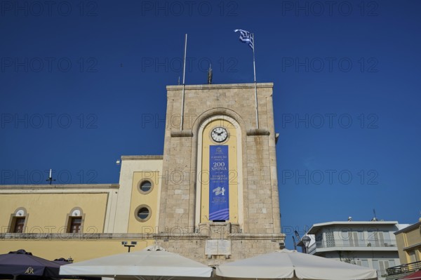 Cinema, Eleftherias Square, Historic clock tower with Greek flag against a clear sky, Kos Town, Kos, Dodecanese, Greek Islands, Greece