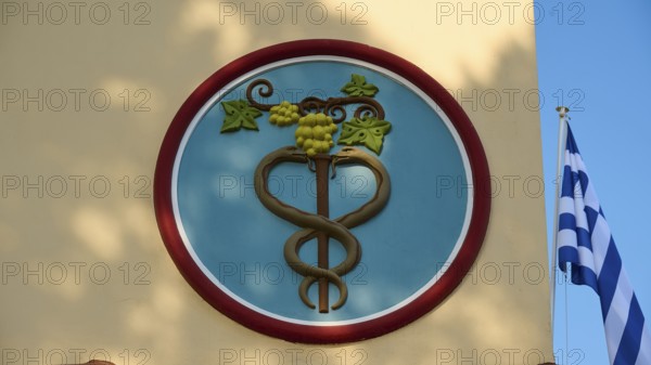 Town Hall, circular emblem with snake and vine, flanked by Greek flag, Kos Town, Kos, Dodecanese, Greek Islands, Greece