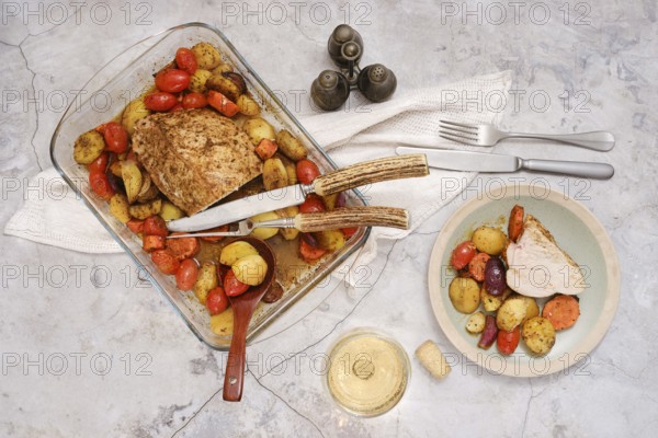 Succulent turkey breast is perfectly roasted alongside vibrant vegetables and potatoes, arranged on a serving dish