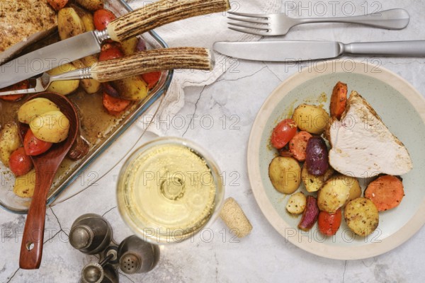 A plate with tender slices of turkey breast alongside colourful roasted vegetables, including potatoes and carrots. A glass of white wine enhances the dining experience