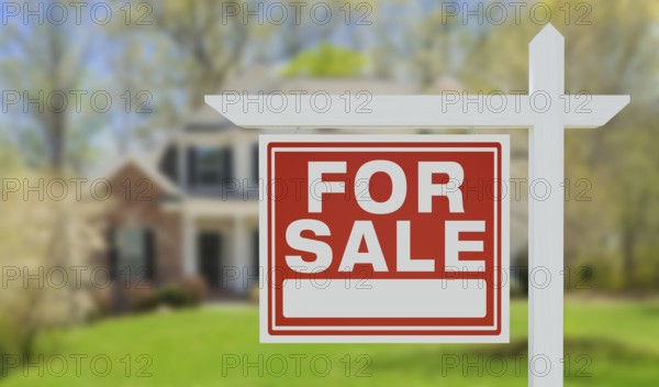 For sale real estate sign in front of beautiful house