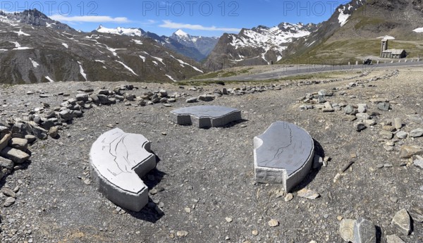 In front three orientation boards on stone for landscapes and mountain peaks at viewpoint next to highest asphalted pass Col d'iseran Pass in Alps High Alps above tree line behind view of mountain landscape with high peaks, Route des Grandes Alpes, Département Savoie, Region Auvergne-Rhône-Alpes, Graian Alps, France