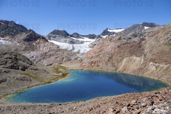 View of blue glacial lake in rocky mountain landscape, behind Königshofspitz, Schwarzwandspitz and Übeltalferner glacier, descent from summit Roter Grat, Stubai Alps, South Tyrol, Italy