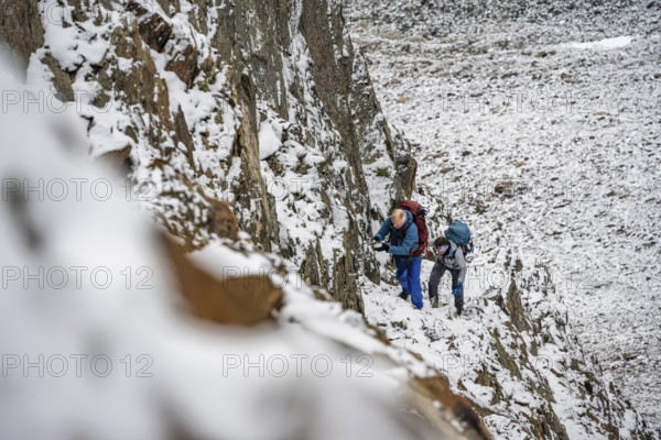 Mountaineer on a rope-secured path in a steep, rocky mountain landscape with fresh snow in summer, ascent to the Hornscharte, Schober Group, Hohe Tauern National Park, Carinthia, Austria