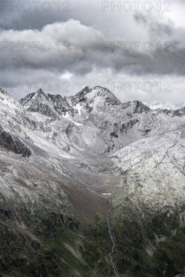 View of steep, rocky mountain landscape with fresh snow in summer, on the Vienna High Trail, Schober Group, Hohe Tauern National Park, Carinthia, Austria