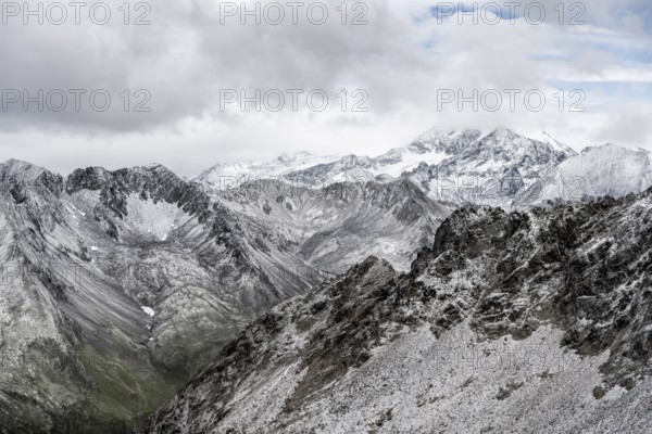 View of steep, rocky mountain landscape with fresh snow in summer, on the Vienna High Trail, Schober Group, Hohe Tauern National Park, Carinthia, Austria