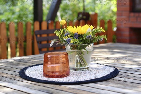 Close up of yellow and purple flower bouquet and storm lamp with candle decoration on table