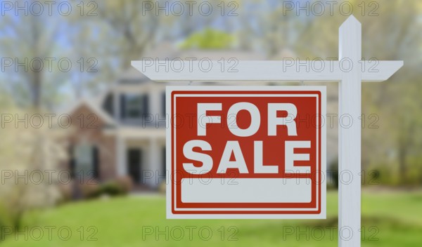 For sale real estate sign in front of beautiful house