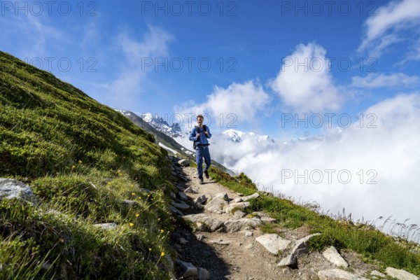 Mountaineer on a hiking trail, inversion weather situation with clouds in the valley, Chamonix, Haute-Savoie, France