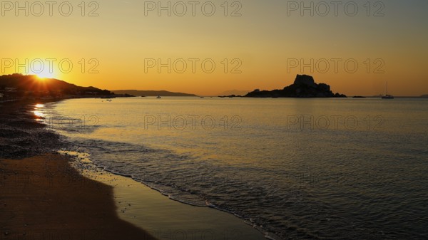 Tranquil sunset with a view of an island and golden sky, Agios Stefanos Beach, Agios Stefanos Basilica, Basilica, Kastri Island, Kos, Dodecanese, Greek Islands, Greece