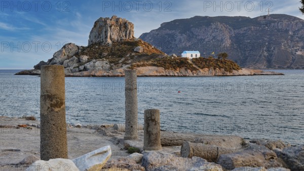 Ancient columns overlooking a rocky island with a blue house in the sea, Agios Stefanos Beach, Agios Stefanos Basilica, Basilica, Kastri Island, Kos, Dodecanese, Greek Islands, Greece