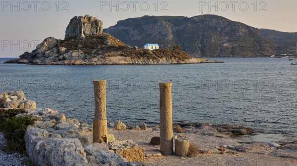 Ancient columns in front of the sea in warm evening light with an island in the background, Agios Stefanos Beach, Agios Stefanos Basilica, Basilica, Kastri Island, Kos, Dodecanese, Greek Islands, Greece