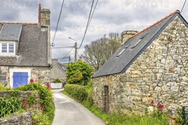 Alley in an old French village with old stone houses with flowers in bloom in the countryside a summer day, Crozon peninsula, Bretagne, France