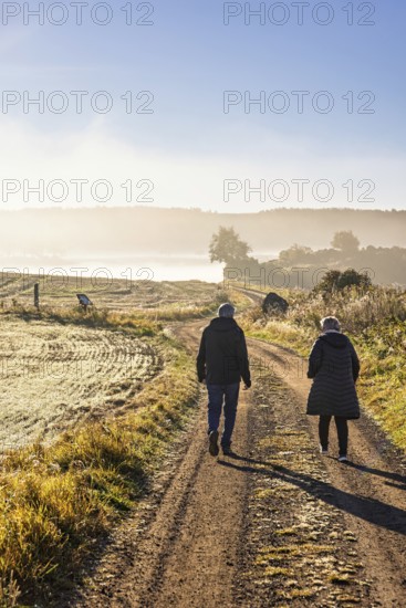 Pair walking on a gravel road in a rural landscape at autumn