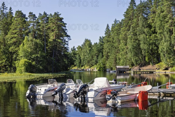 Motorboats at a jetty in a forest lake on a beautiful sunny summer day, Sweden