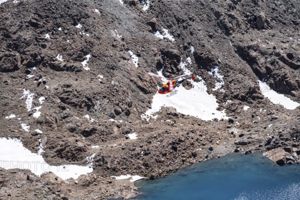 Red helicopter flying in the mountains, Stubai Alps, South Tyrol, Italy