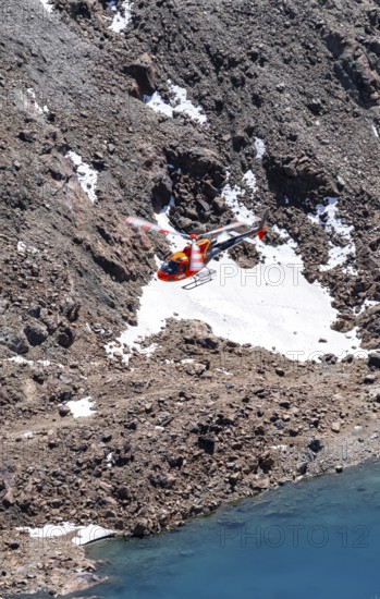 Red helicopter flying in the mountains, Stubai Alps, South Tyrol, Italy