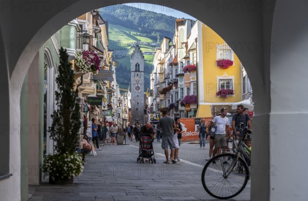 Passageway, old town, colourful houses in the main street, Zwölferturm tower at the back, Sterzing, South Tyrol, Italy
