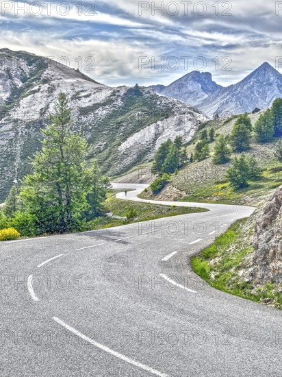 Photo with reduced dynamic saturation HDR of south ramp ascent of steep pass road with tight curves steeply ascending to mountain pass Alpine pass Col d'Izoard, Col de l'Izoard, Cottian Alps, Route des Grandes Alpes, Département Hautes-Alpes, France