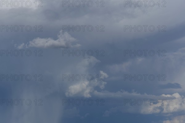Dark storm clouds gather in the sky over a vast rural landscape, signalling an impending summer downpour. The atmosphere feels burdened by the impending weather. Bas rhin, Alsace, grand est, France