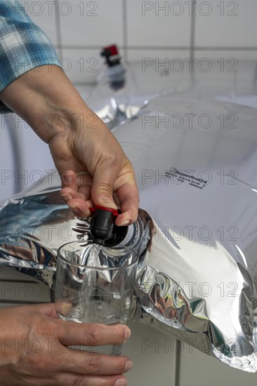 Tapping water from a 10 litre water bag, for storing drinking water at home, as an emergency reserve in the event of a blackout or similar, lightweight, foldable, reusable bag made of multi-layer film, with tapping device, for long-term storage of up to one year, recommended 3 litres of drinking water per person, for 10 days of storage