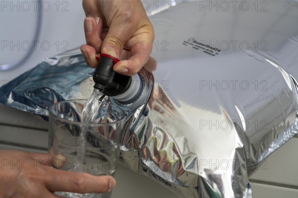 Tapping water from a 10 litre water bag, for storing drinking water at home, as an emergency reserve in the event of a blackout or similar, lightweight, foldable, reusable bag made of multi-layer film, with tapping device, for long-term storage of up to one year, recommended 3 litres of drinking water per person, for 10 days of storage