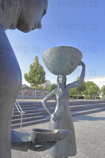 Sculpture Shoe Carrier by Martin Schöneich 2015, monument to woman during the development of the former shoe industry, shoe production, bronze sculpture, modern art, shoe, female figure, carrying a large basket on her head, face, view from below, symbol, cobbler, carrier, presentation, show, Joseph-Krekeler-Platz, Alte Post, shoe carrier, Pirmasens, Rhineland-Palatinate, Germany