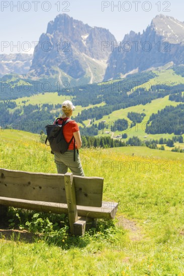 Person looking from a bench at the impressive mountain landscape, Alpe di Siusi, Dolomites, South Tyrol, Italy