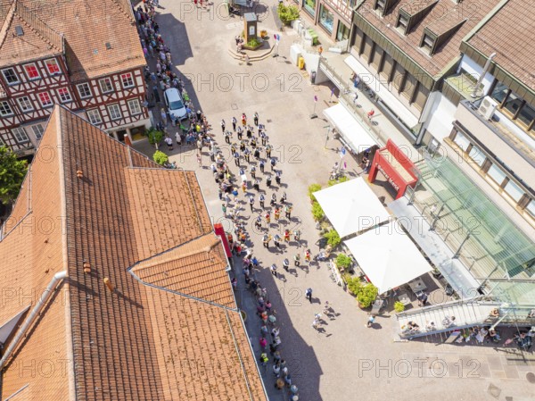 Aerial view of a parade through the centre of a sunny half-timbered town with crowds of people, 950 years of Calw, Calw parade, Black Forest, Germany