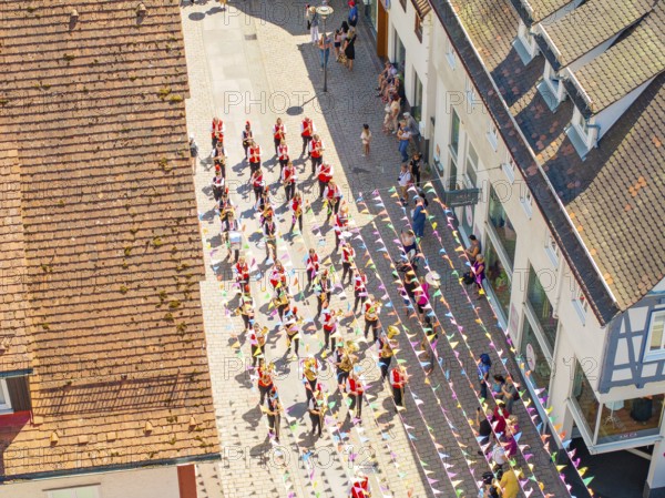 Bird's eye view of a crowd of people in colourful costumes during a street parade between old houses, 950 years Calw, Calw parade, Black Forest, Germany