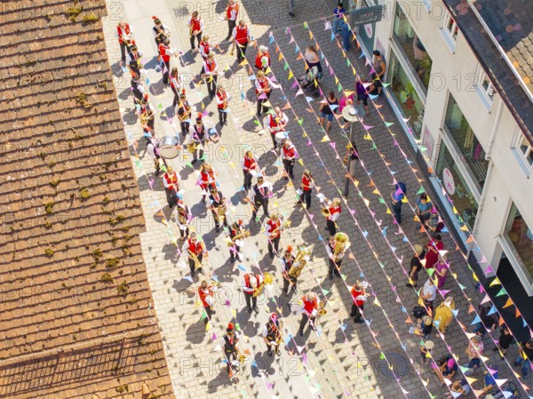 Parade with people in colourful outfits on a street decorated with flags, taken from a bird's eye view, 950 years Calw, parade Calw, Black Forest, Germany