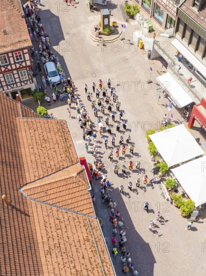 Aerial view of a parade through the alleys of a half-timbered town in sunshine with a crowd of people, 950 years of Calw, Calw parade, Black Forest, Germany