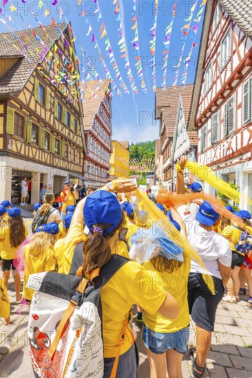 A festive group with flags in a decorated alleyway in the old town centre, 950 years of Calw, Calw parade, Black Forest, Germany