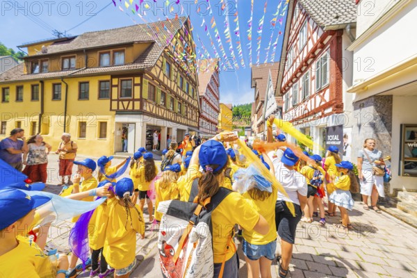 Children in yellow T-shirts and blue caps at a street parade in summer. Festive atmosphere with colourful flags, 950 years of Calw, Calw parade, Black Forest, Germany