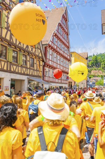 Crowd of people with orange and yellow balloons at a town festival in a half-timbered house setting, 950 years of Calw, Calw parade, Black Forest, Germany