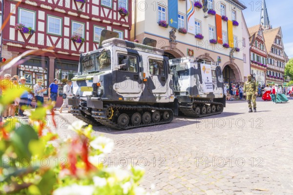 Two military vehicles in front of a row of historic half-timbered houses and surrounded by blooming flowers, 950 years of Calw, Calw parade, Black Forest, Germany