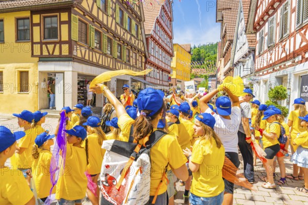 Cheerful children in yellow clothes and blue hats parade through an old town with half-timbered houses, 950 years of Calw, Calw parade, Black Forest, Germany