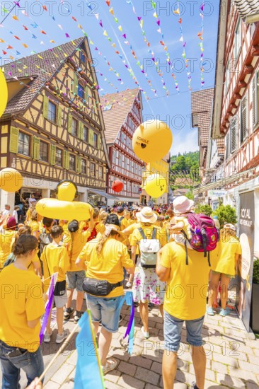 A colourful parade with yellow balloons moves through lively streets lined with half-timbered houses, 950 years of Calw, Calw parade, Black Forest, Germany